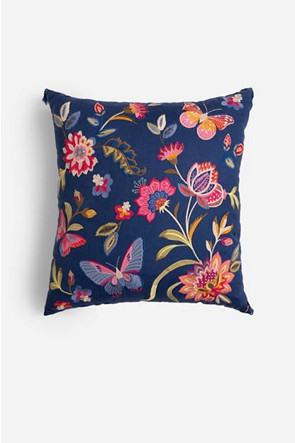 a blue pillow with colorful flowers and butterflies on it