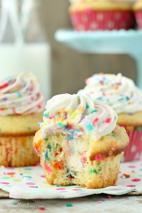 cupcakes with white frosting and sprinkles on a plate