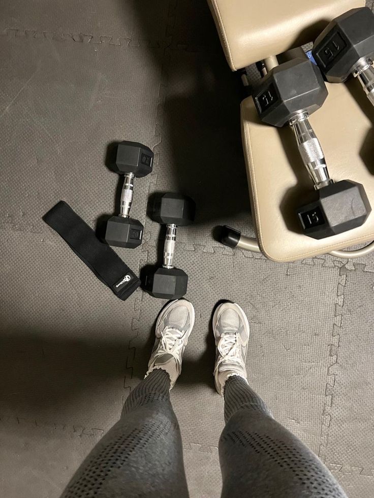 a person standing next to some dumbbells and a chair with their feet on the floor