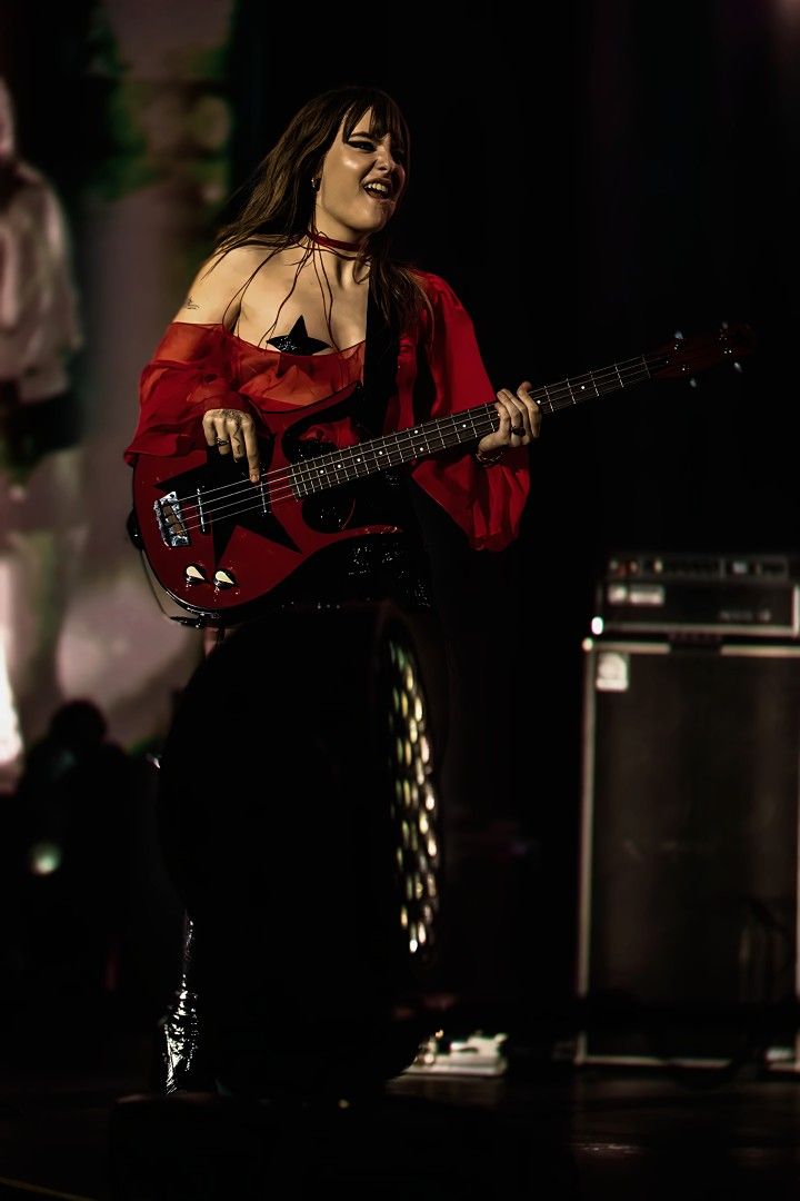 a woman in red shirt playing guitar on stage