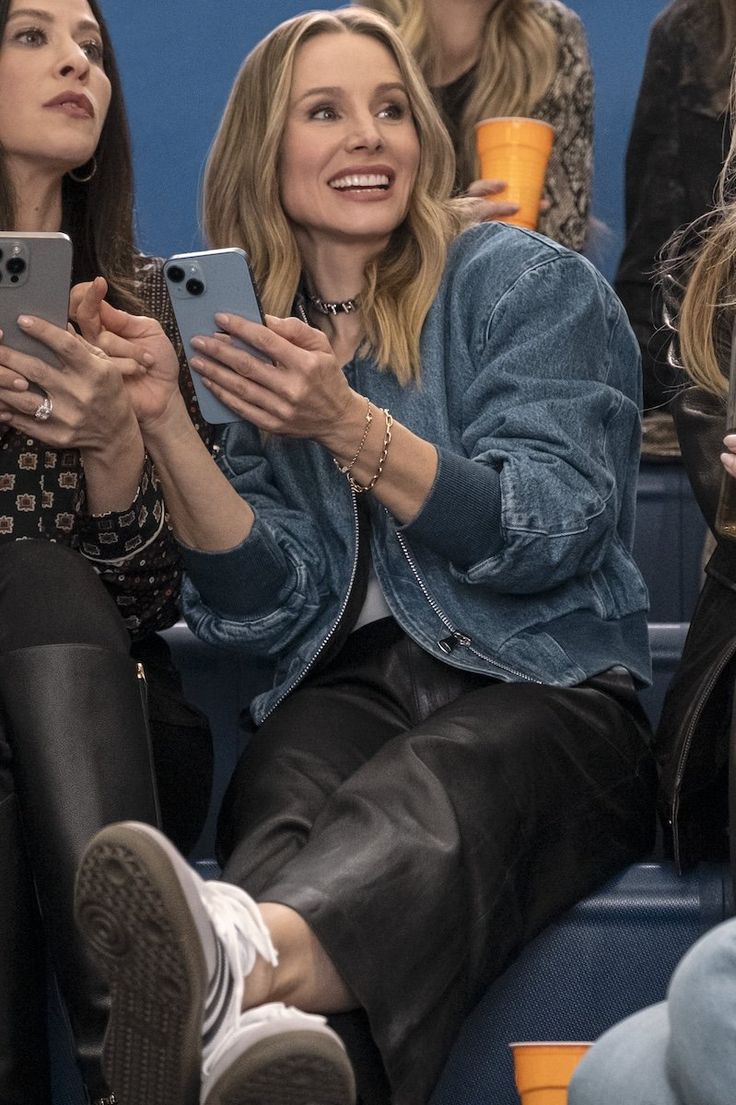 two women sitting next to each other while looking at their cell phones in front of them