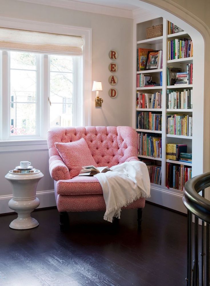 a living room filled with furniture and a book shelf full of books next to a window