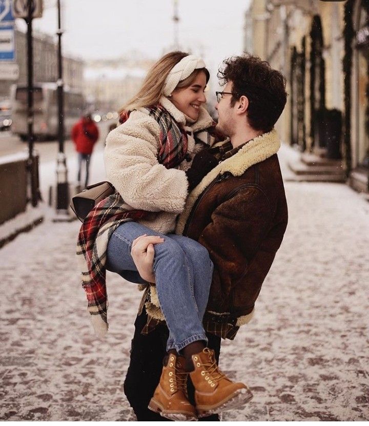 a man carrying a woman on his back in the middle of a snowy city street