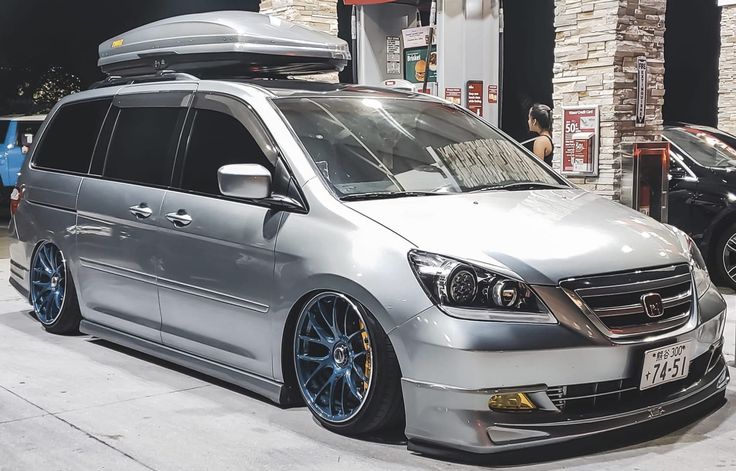 a silver van parked in front of a building with luggage strapped to it's roof