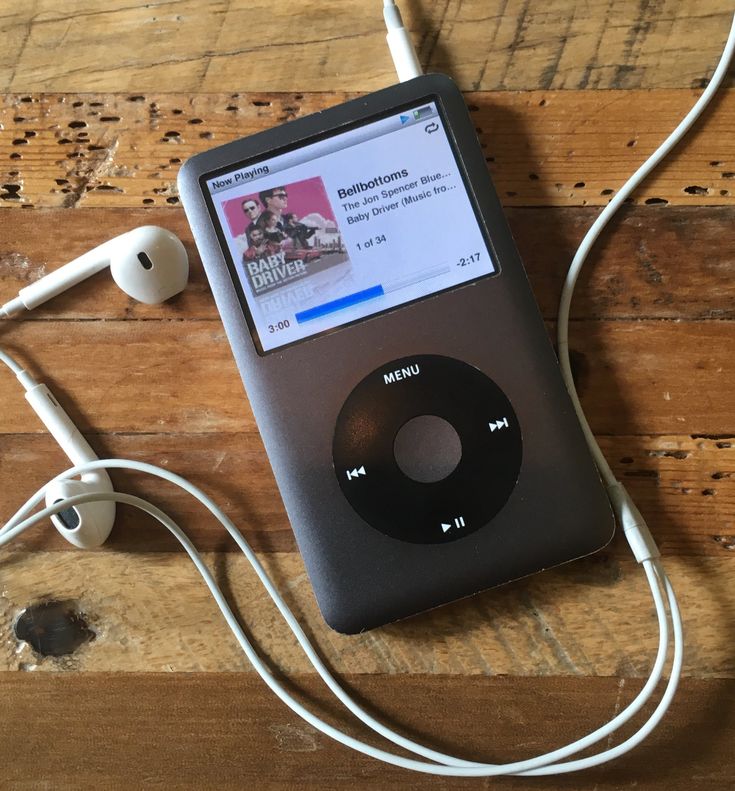 an ipod is plugged into ear buds on a wooden table with wood planks