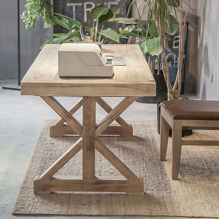 a wooden table sitting on top of a rug next to a chair and potted plant