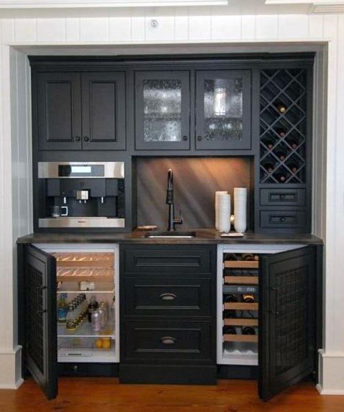 a kitchen with black cabinets and an open wine cooler in the center, along with wooden flooring