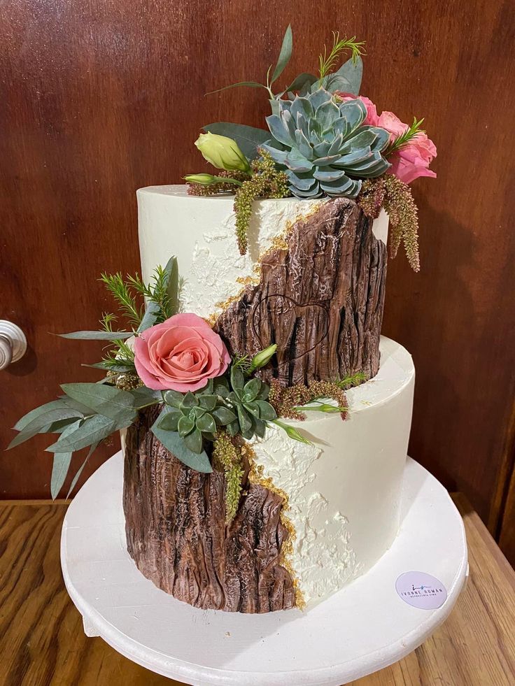 a three tiered cake decorated with succulents and flowers on a white plate