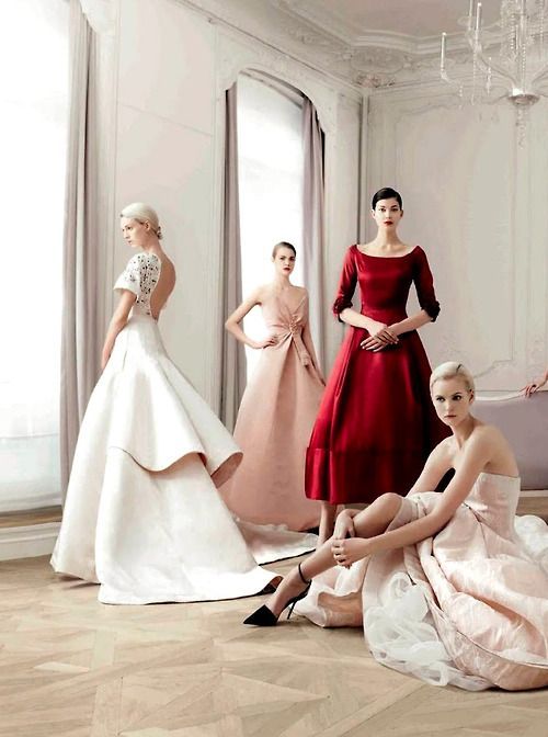 a group of women in dresses sitting on the floor with one woman standing next to her