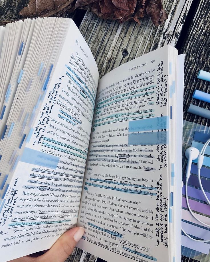 an open book sitting on top of a wooden table next to headphones and earbuds