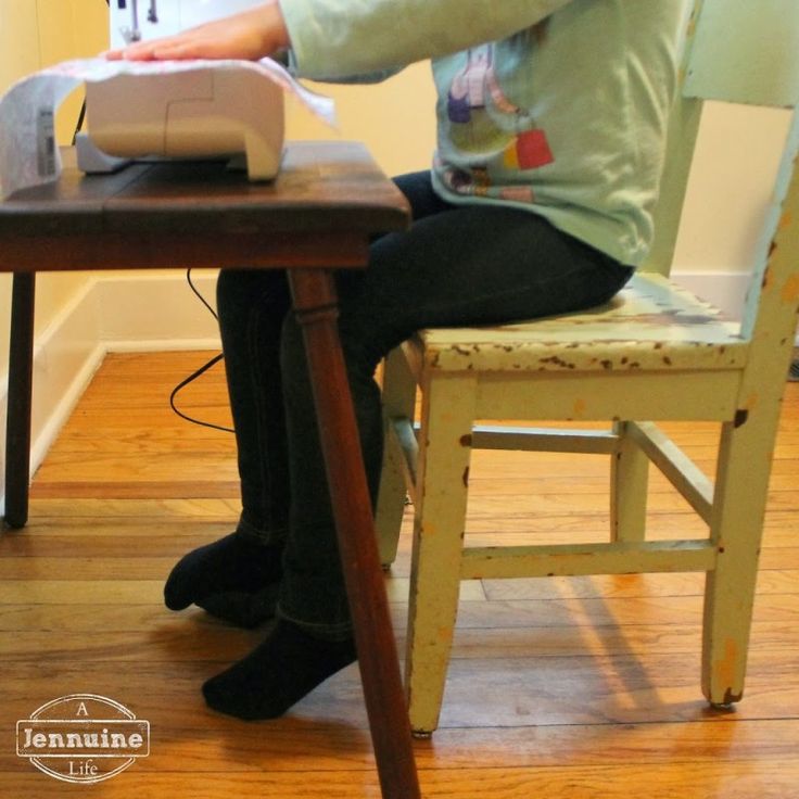 a woman sitting at a table using a sewing machine