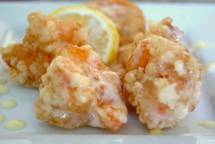 some food is sitting on a plate with lemon wedges and drizzled icing