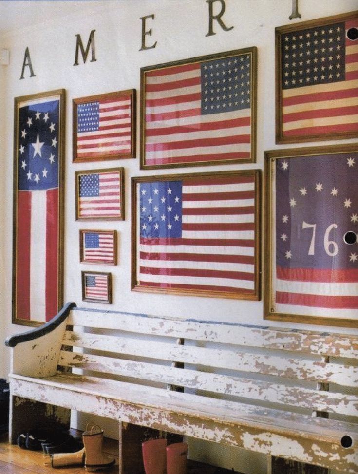 a white bench sitting in front of a wall with american flags hanging on it's sides