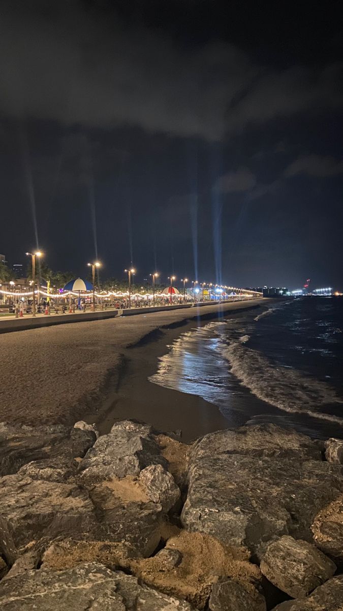 the beach is lit up at night with bright lights on it's sides and dark clouds in the sky