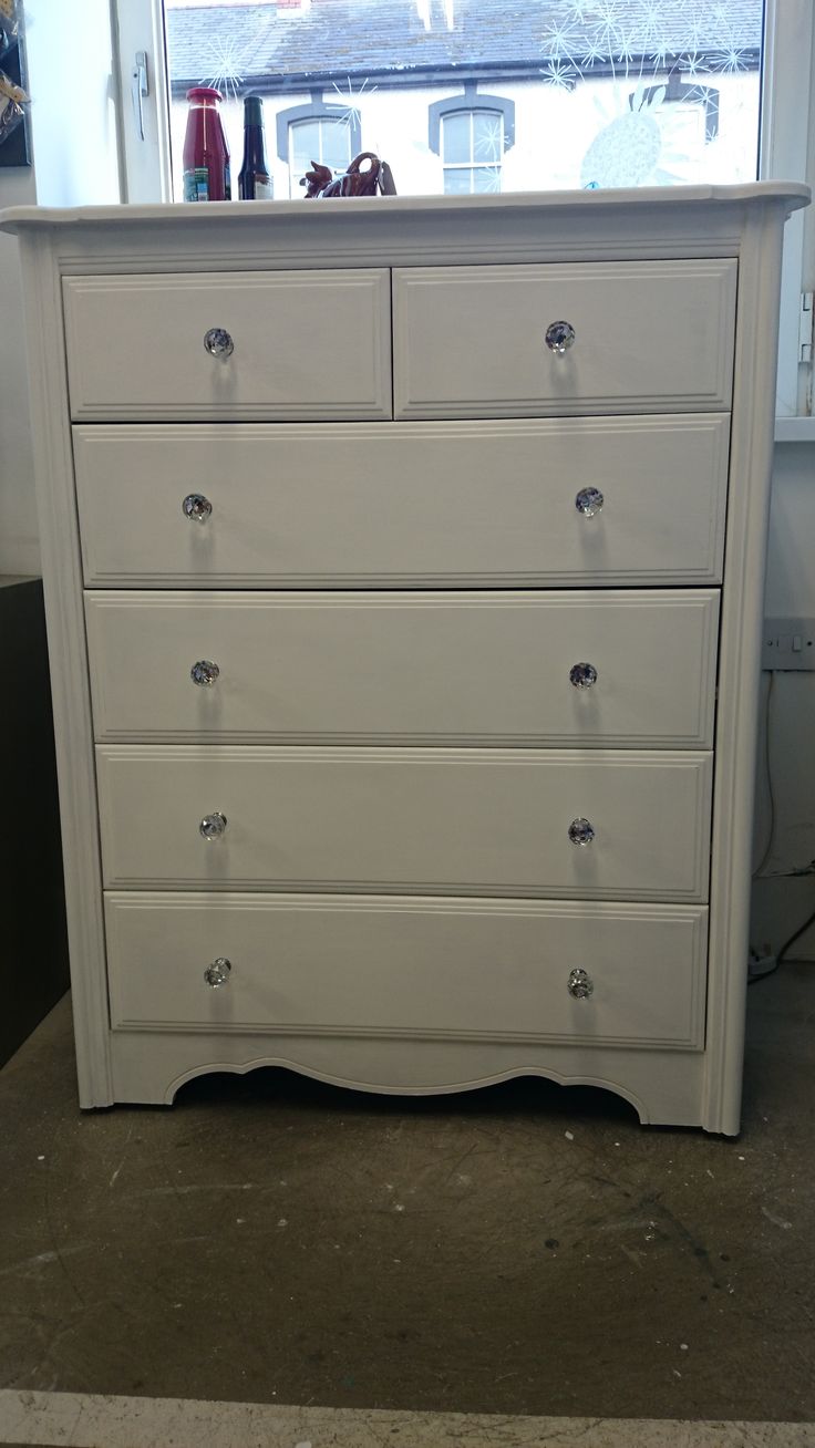 a white dresser sitting in front of a window