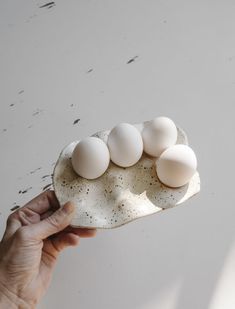 a person holding an egg shell with six eggs in it on the white table top