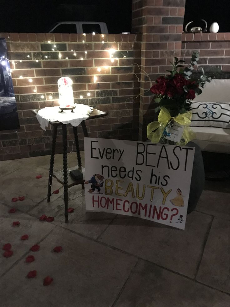 a sign sitting on the side of a brick wall next to a planter with flowers