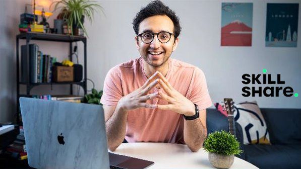 a man sitting at a table in front of a laptop computer with his hands together