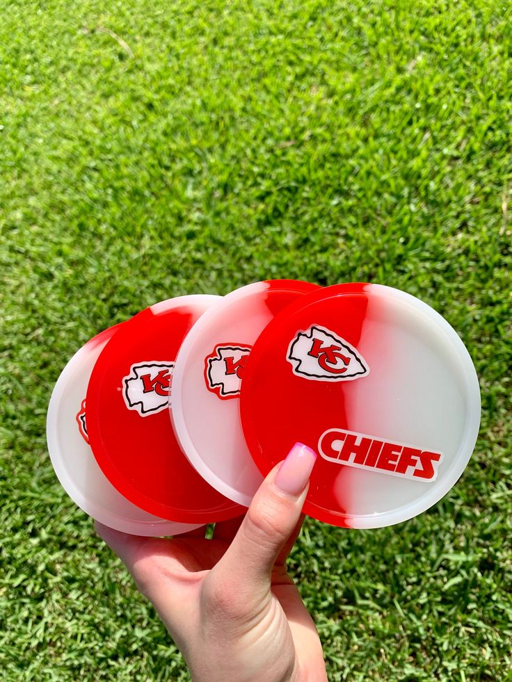 two red and white frisbees with the word chiefs on them in front of grass