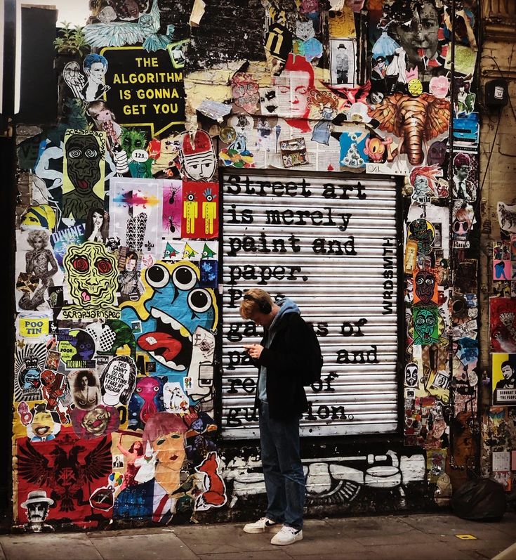 a man standing in front of a wall covered with stickers