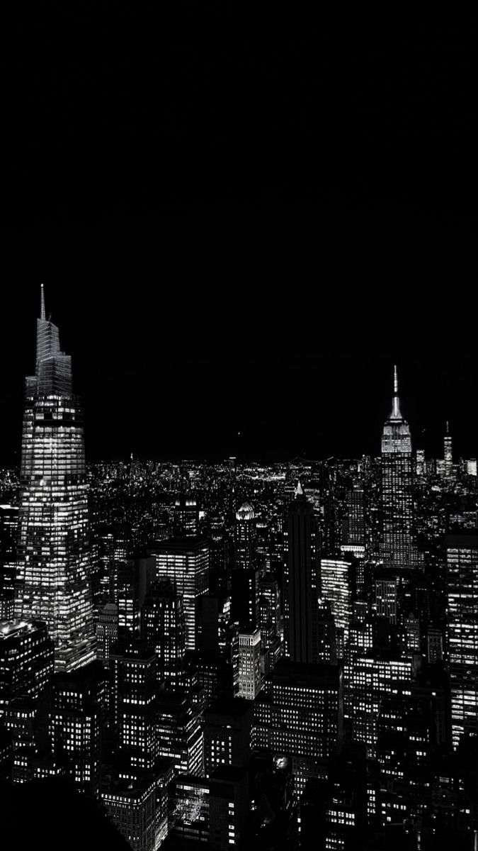 black and white cityscape at night with skyscrapers lit up in the distance