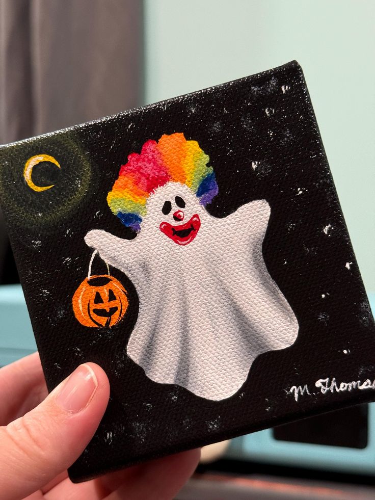 a hand holding up a halloween card with a clown painted on it