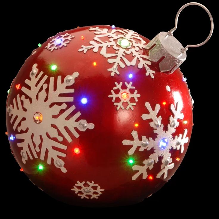 a red ornament with white snowflakes and lights on it's side