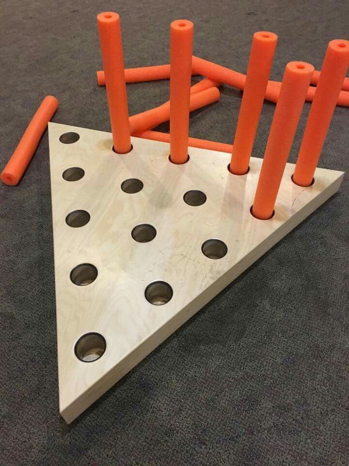 an orange piece of wood with holes in it on the floor next to some orange sticks