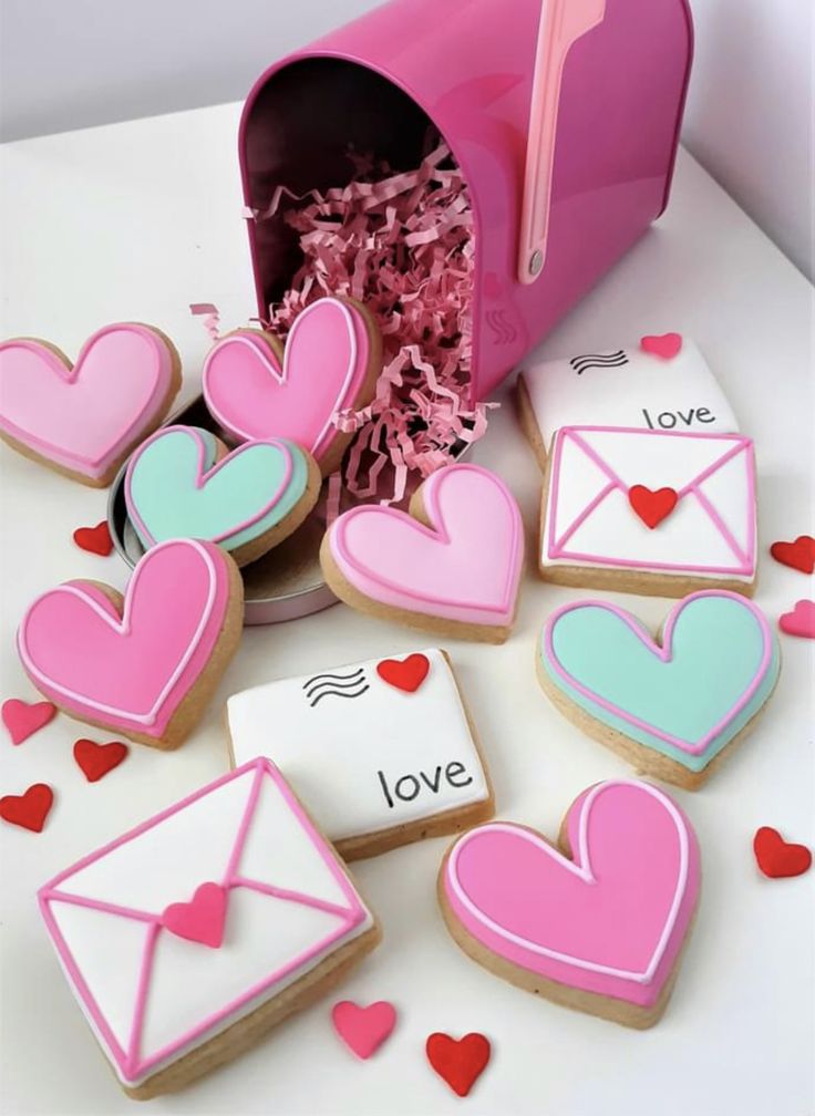 decorated cookies in the shape of envelopes and hearts are sitting on a white table