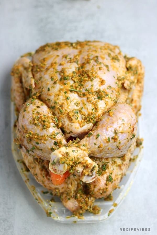 chicken with herbs and seasoning in a glass dish