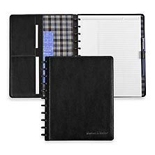 a black notebook with a checkered cover and pen in it, next to an empty note book