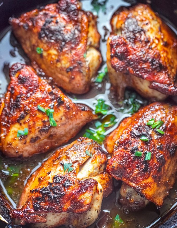 some meat is cooking in a pan with sauce and herbs on the side, ready to be eaten