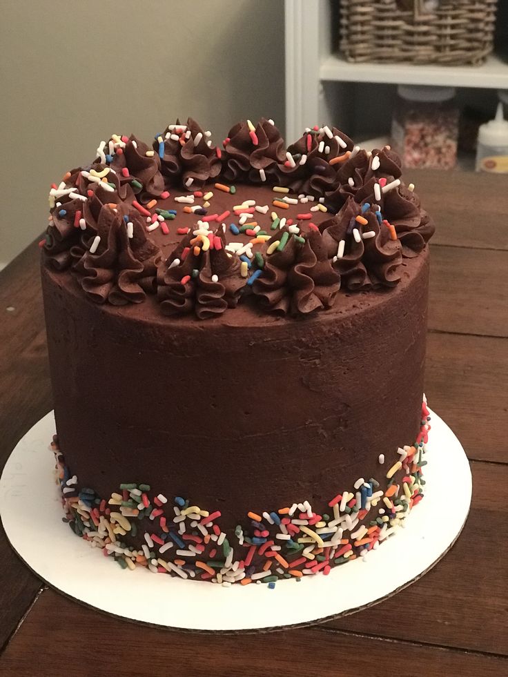 a chocolate cake topped with sprinkles on top of a wooden table