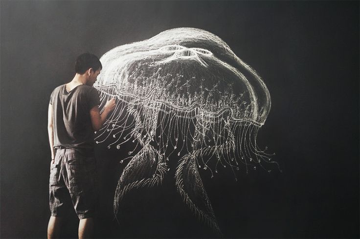 a man standing in front of a drawing of a jellyfish on a black background