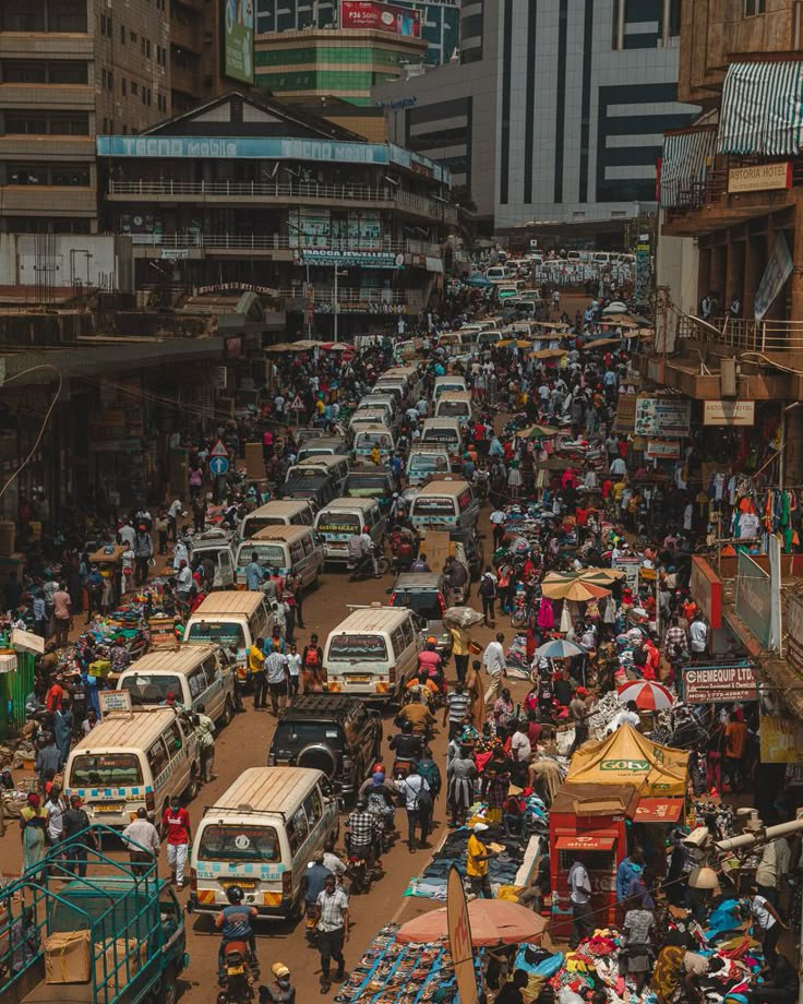 a busy city street filled with lots of traffic and people walking around it, surrounded by tall buildings