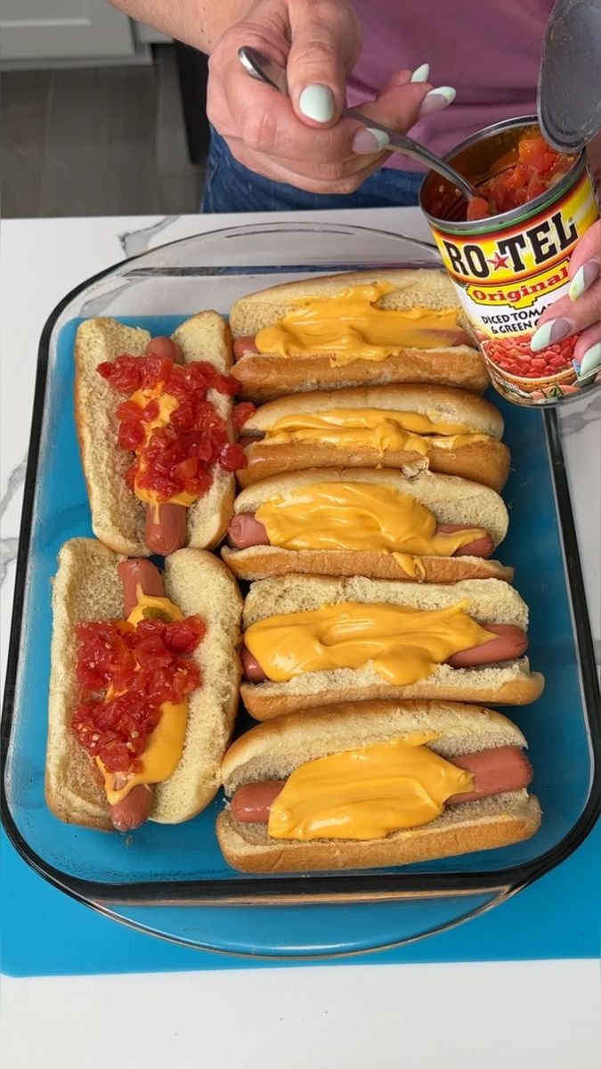 hotdogs with mustard and ketchup are on a blue platter next to a can of salsa