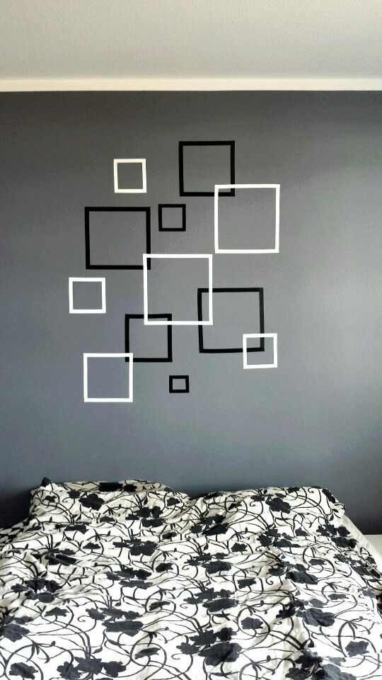 a bed with a black and white bedspread in front of a gray wall