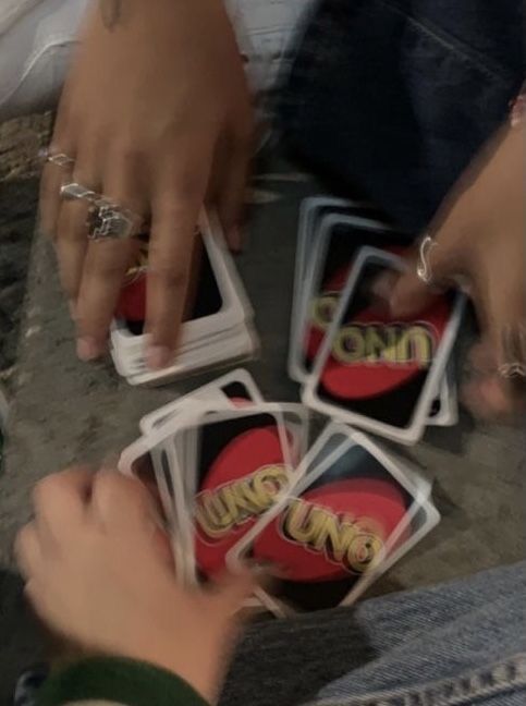 several people are playing cards on the ground with their hands holding onto each other's fingers