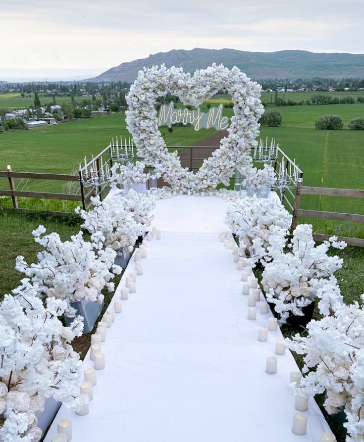 a white wedding aisle decorated with flowers and candles