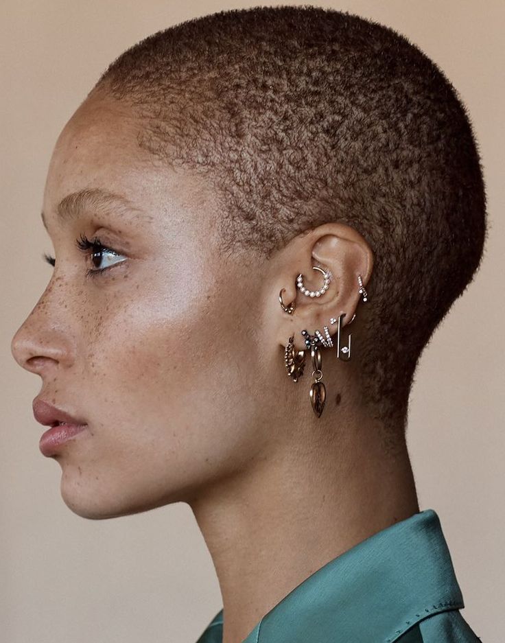 a close up of a person with short hair and earrings on her head, wearing a green shirt