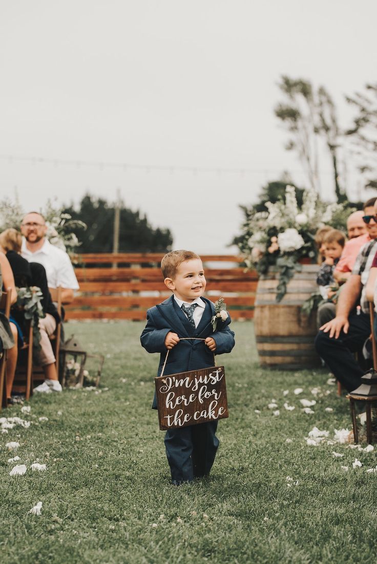 a little boy in a suit and tie holding a sign