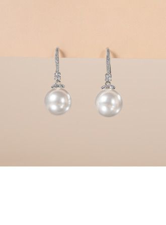 pair of earrings with white pearls and diamonds on top of a beige background, close up