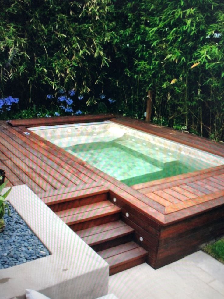 an outdoor hot tub in the middle of a garden