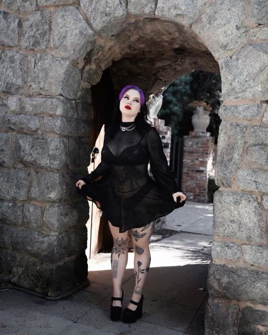 Get ready to rock this Beetle Babe Mini Dress in Black Spiderweb Mesh, goth goddess! This dress will have you channeling the ultimate spooky babe, Lydia Deetz, with its flared sleeves and mock turtleneck. Create a wicked and witchy look any day, not just Halloween, with this high-quality sheer stretch mesh dress featuring a metallic spider web print. You'll feel like a dark and mysterious babe with the cinched waist and pointed hem. 🕷️ Check out bodysuit section for the perfect onepiece to wear Halloween Fairy Grunge Mini Dress For Night Out, Fairy Grunge Mini Dress For Halloween Night Out, Black Witchy Mini Dress For Costume Party, Gothic Sheer Mini Dress For Night Out, Witchy Evening Mini Dress, Halloween Alternative Style Mini Dress, Gothic Black Sheer Dresses, Witchy Dresses For Halloween Festival, Edgy Mini Dress For Halloween Evening