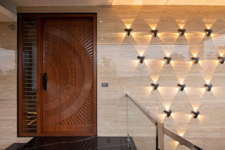 the entrance to a modern home with decorative lights on the wall and stairs leading up to it