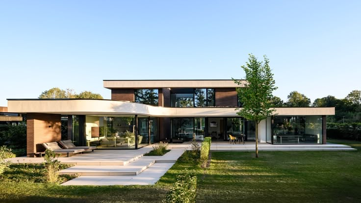 a modern house with grass and trees in the front yard, as well as steps leading up to it