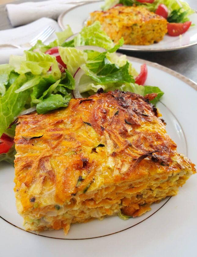 two white plates with food on them and salad in the middle one plate has a slice of vegetable lasagna