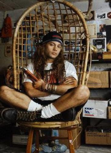 a man sitting in a chair with long hair and dreadlocks on his feet