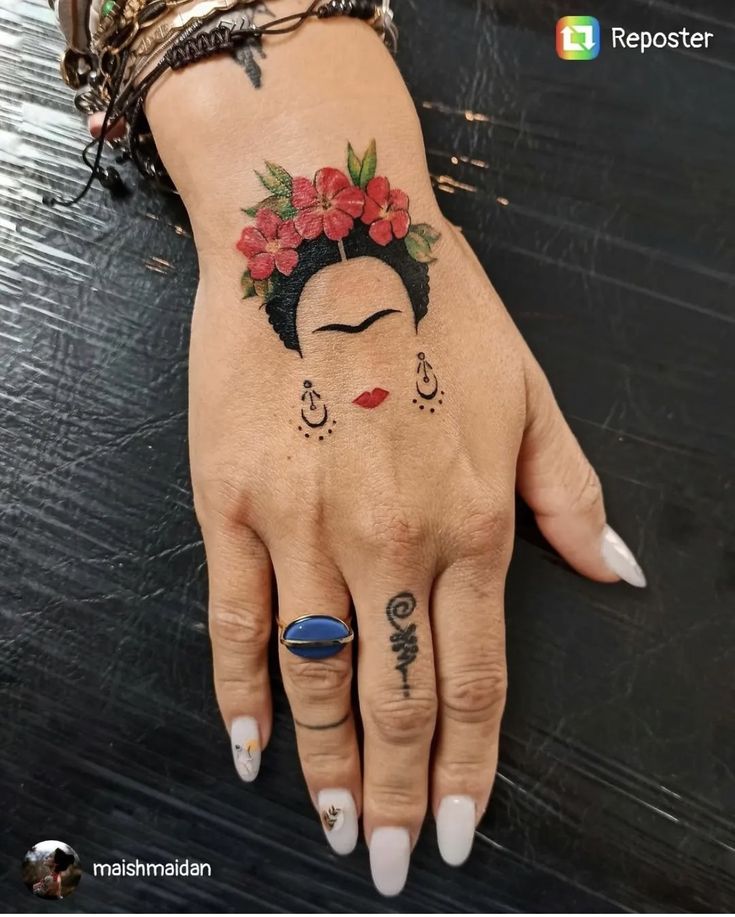 a woman's hand with tattoos on it and flowers in her hair is shown