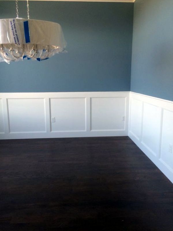 empty room with blue walls and white wainscothes on the wall, chandelier hanging from ceiling